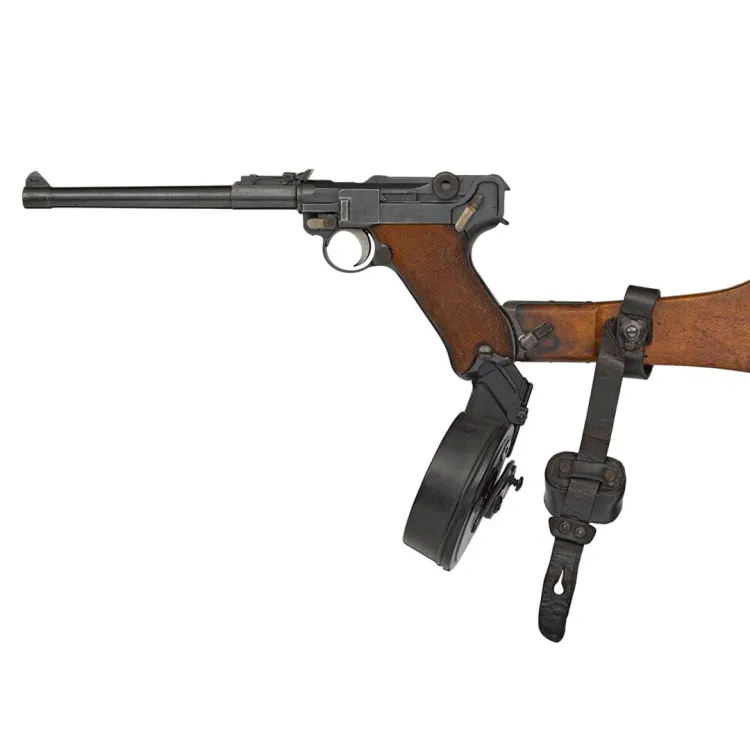 A long barrelled pistol with a drum magazine and wooden buttstock attached