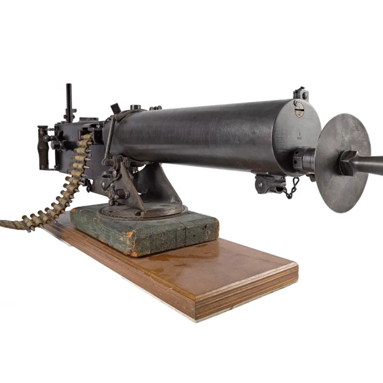 A black, belt-fed machine gun with smooth cylindrical barrel jacket mounted on a wooden block