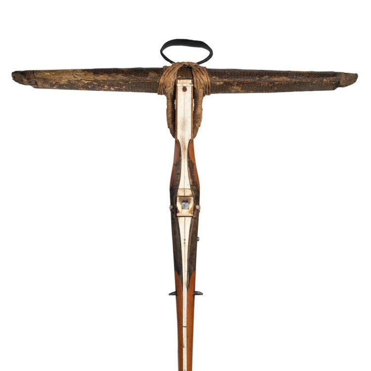 An ornate crossbow made with wood, horn or ivory, and metal. The construction forms a T shape.
