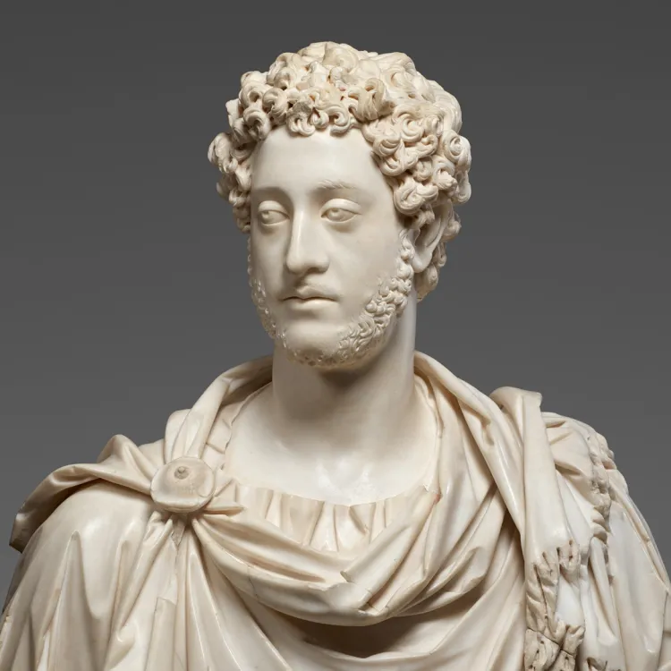 A marble bust of a bearded figure in robes against a dark grey background