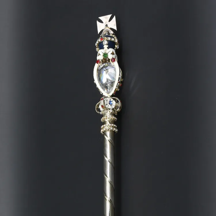A golden rod topped with a inlaid diamond and a diamond encrusted golden cross