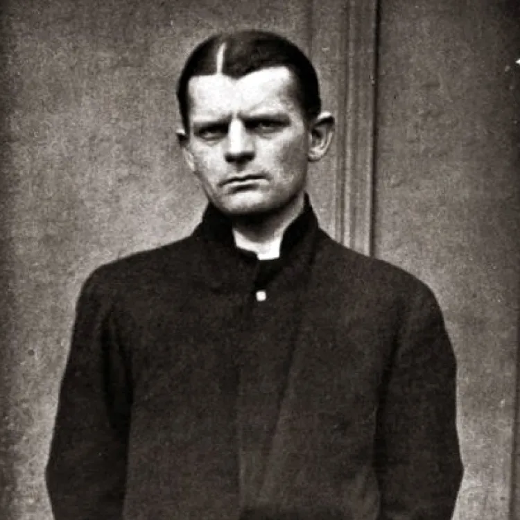 A black and white photograph of a man with neatly parted hair and a dour expression in a long dark coloured coat