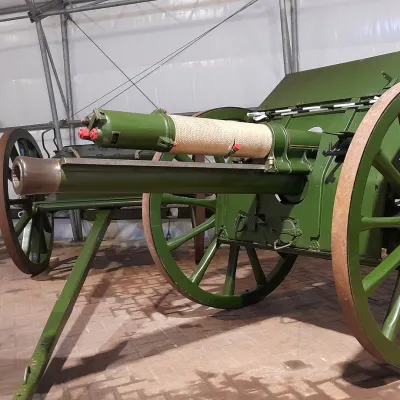 A green 18-pounder cannon with field carriage in a grey hanger