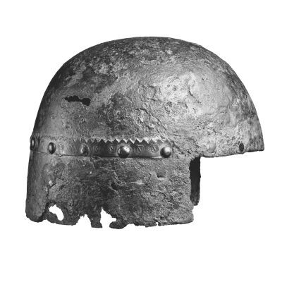 A metal helmet. The lower edge is cut away in front to form a square face opening, the metal is corroding 
