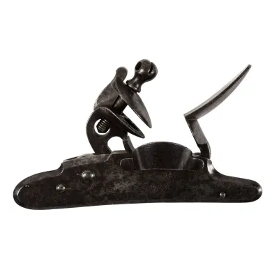 A detached lock from a flintlock musket, completely of steel