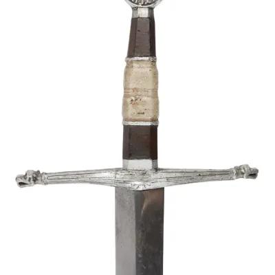 A decorated hilt of a sword with the blade facing down