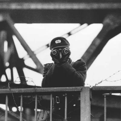 East German policeman observing through binoculars