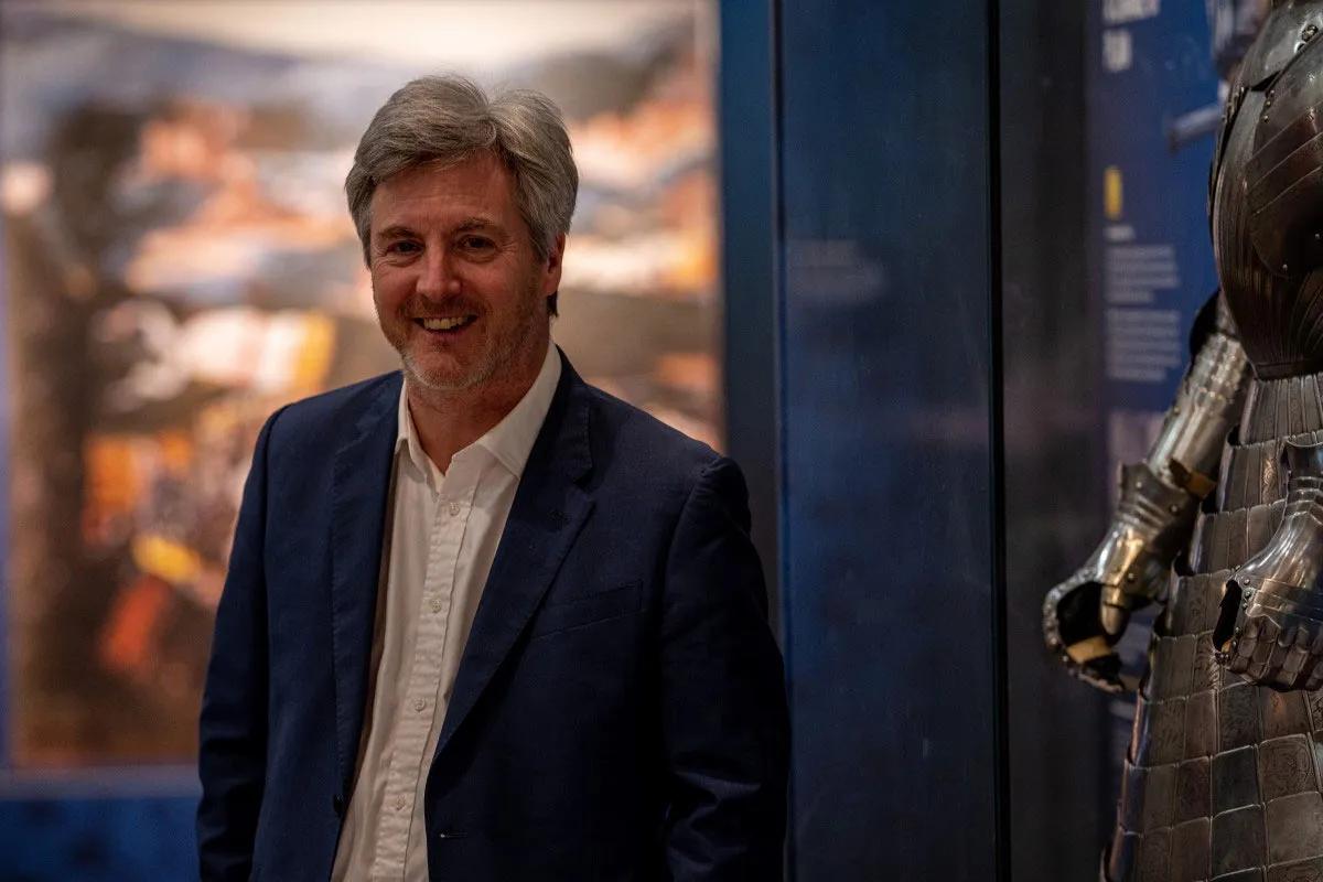 Chief Operating Officer Rod Taylor stands next to a glass case containing armour in Tournament gallery