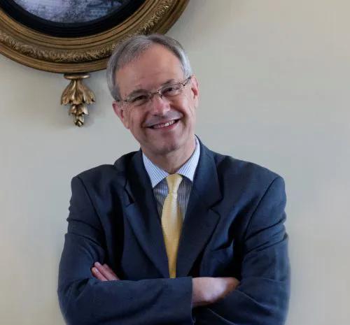 Professor Steven Gunn, a smiling man with glasses standing with arms folded