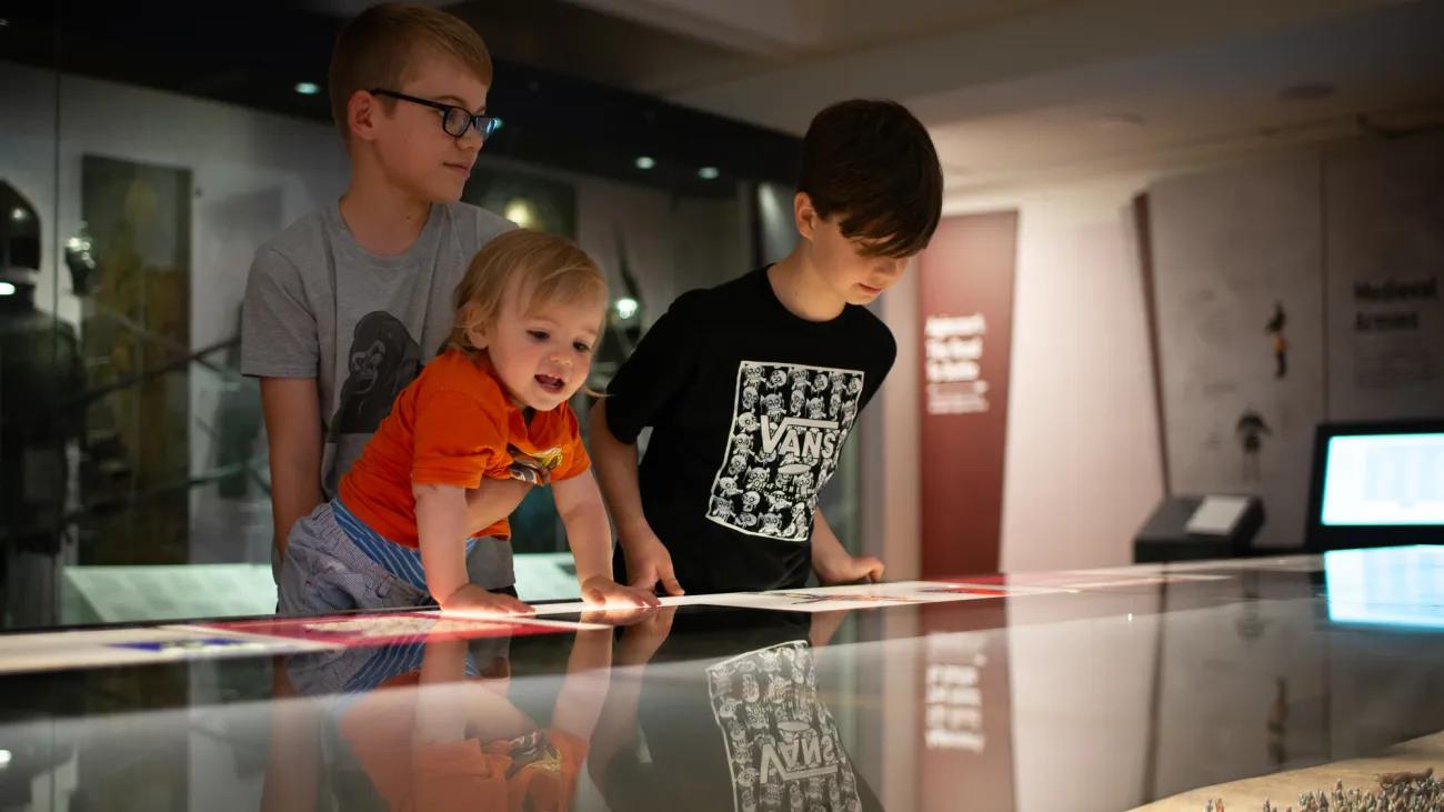 three excited children getting a better look at the Agincourt model