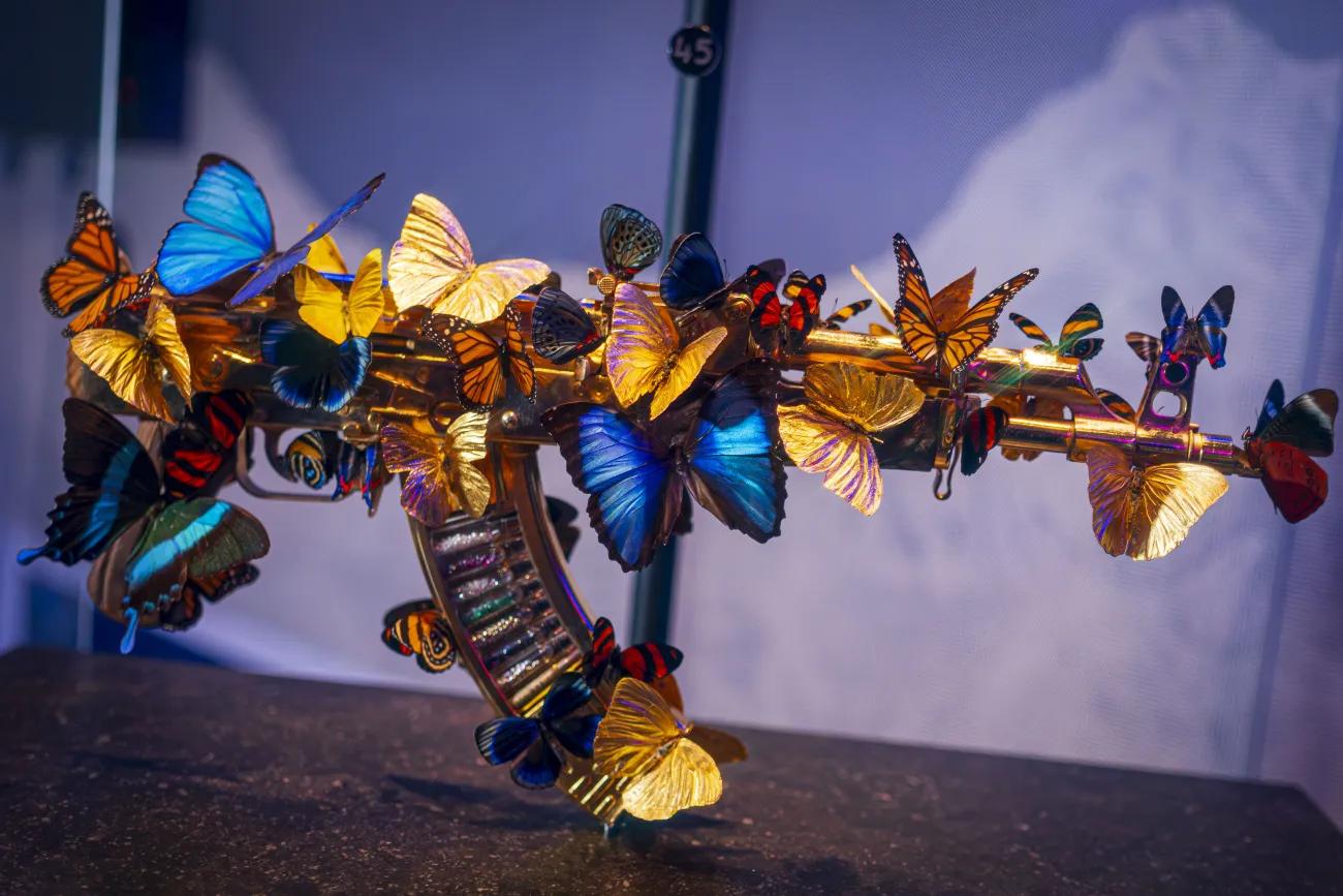 AK 47 embellished with multiple coloured butterflies