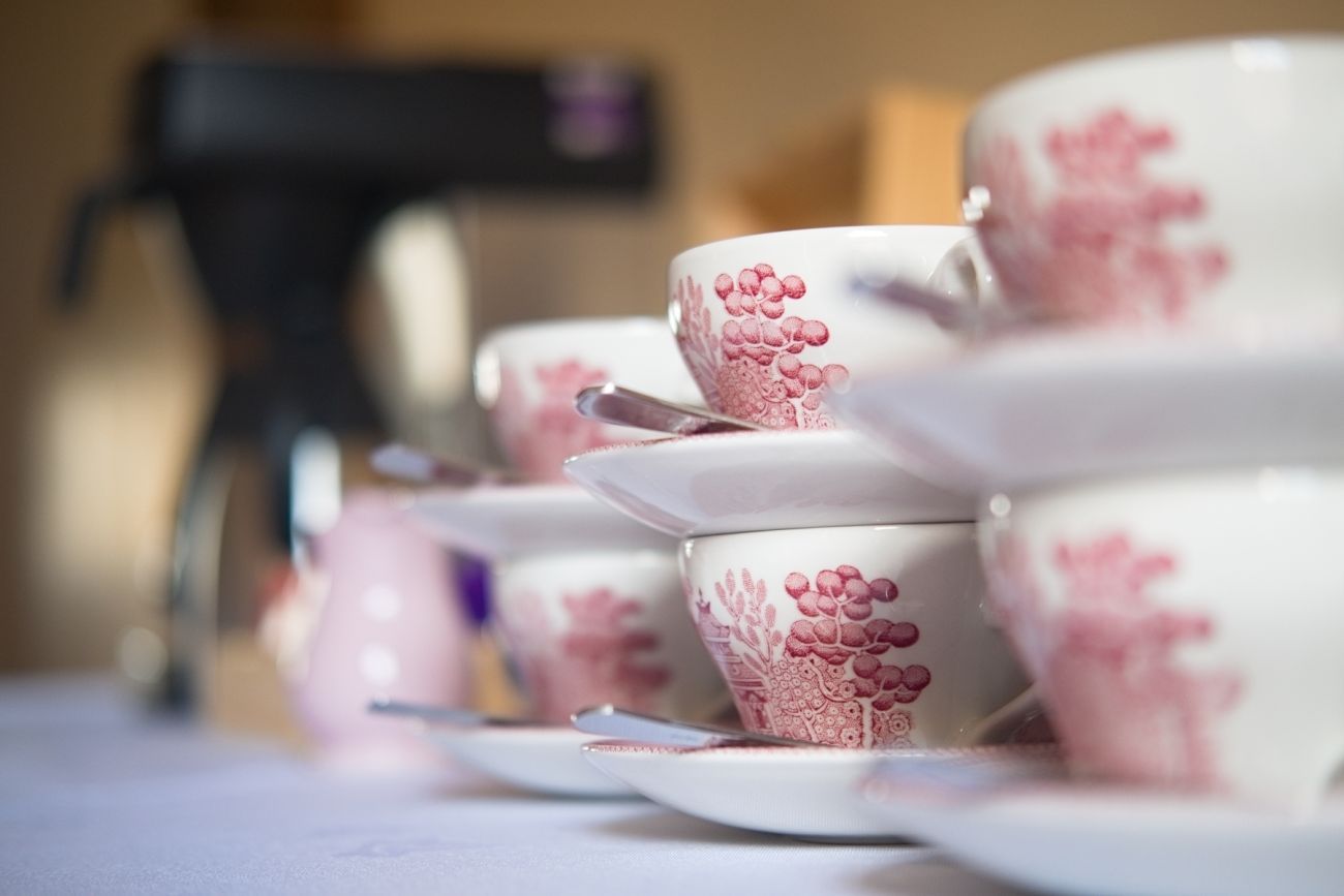 White tea cups and saucers with pink decoration stacked two high