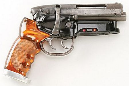 A profile of a gun pointing to the right. The gun is made of steel and has an orange grip