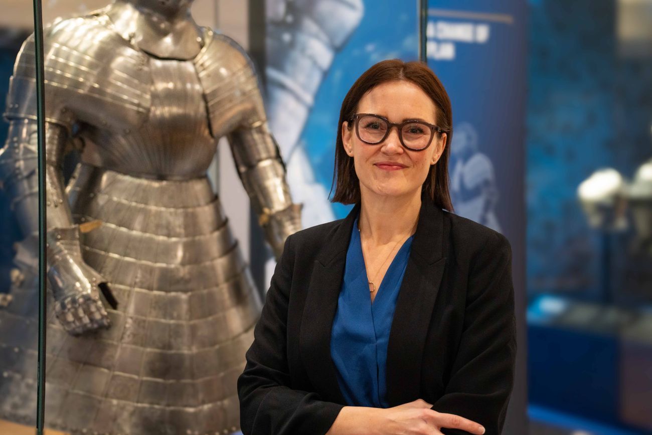 Sofi Lundgren standing in front of a display case of full armour