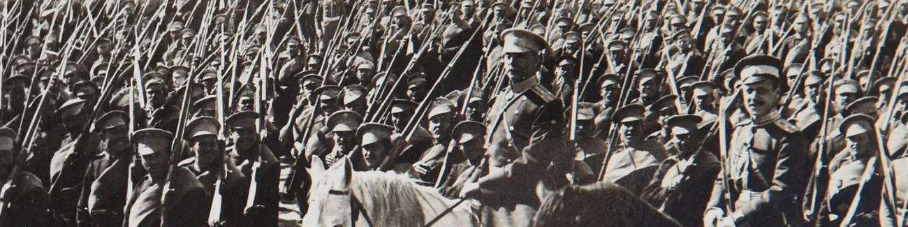 Hundreds of Russian soldiers carrying rifles with bayonets parade past an officer for review