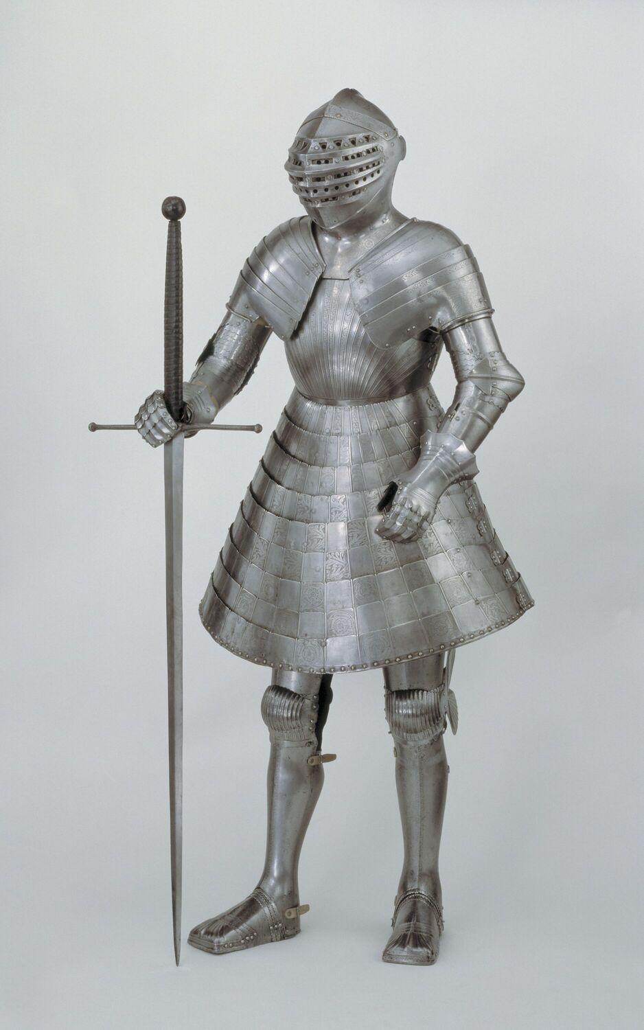 A full length suit of armour with a skirt and sword