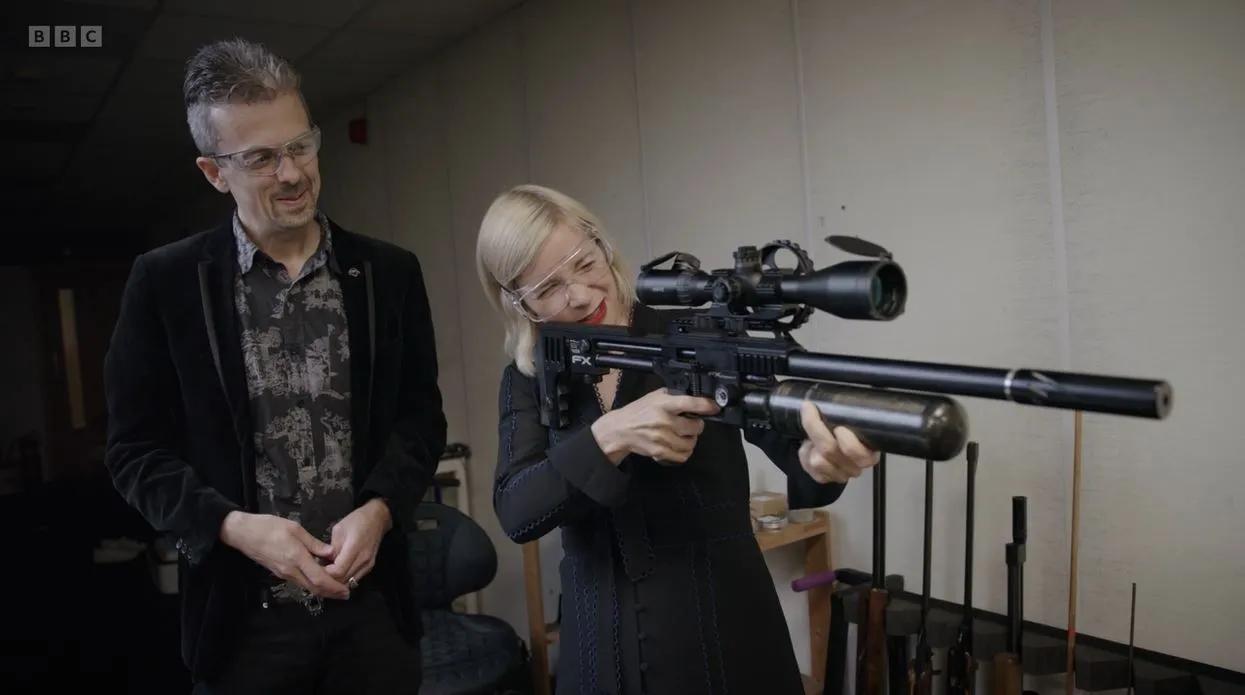 Lucy Worsley aiming a firearm stood next to Jonathan Ferguson