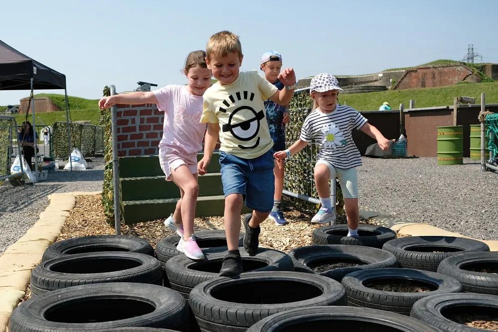 Four children walking across tyres laid flat