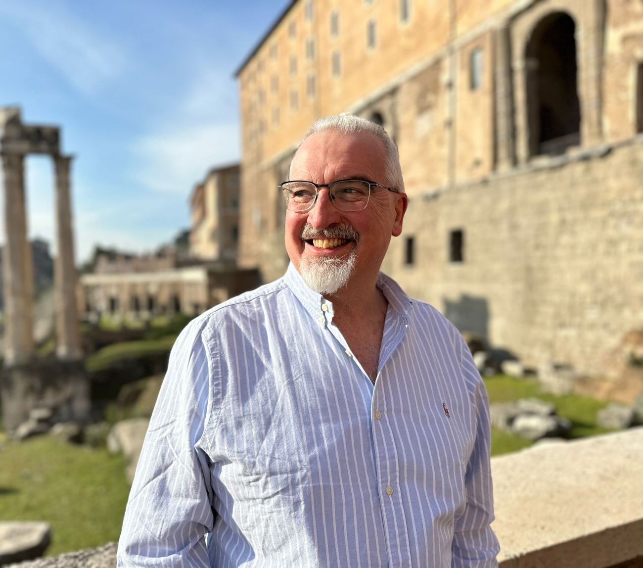 White middle aged man in striped shirt with spectacles