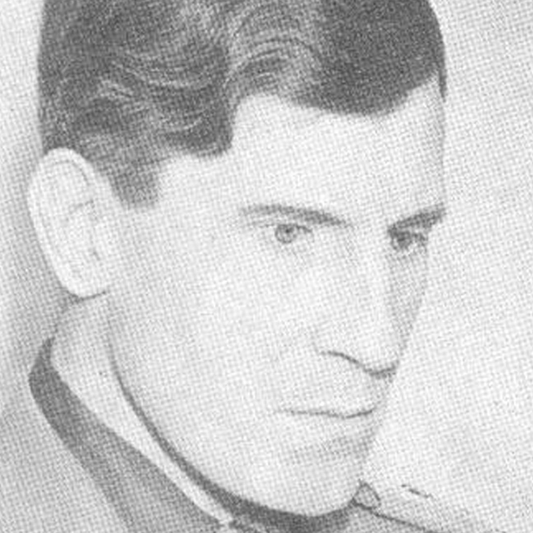 A black and white photograph of a lean-faced man with neat, wavy hair