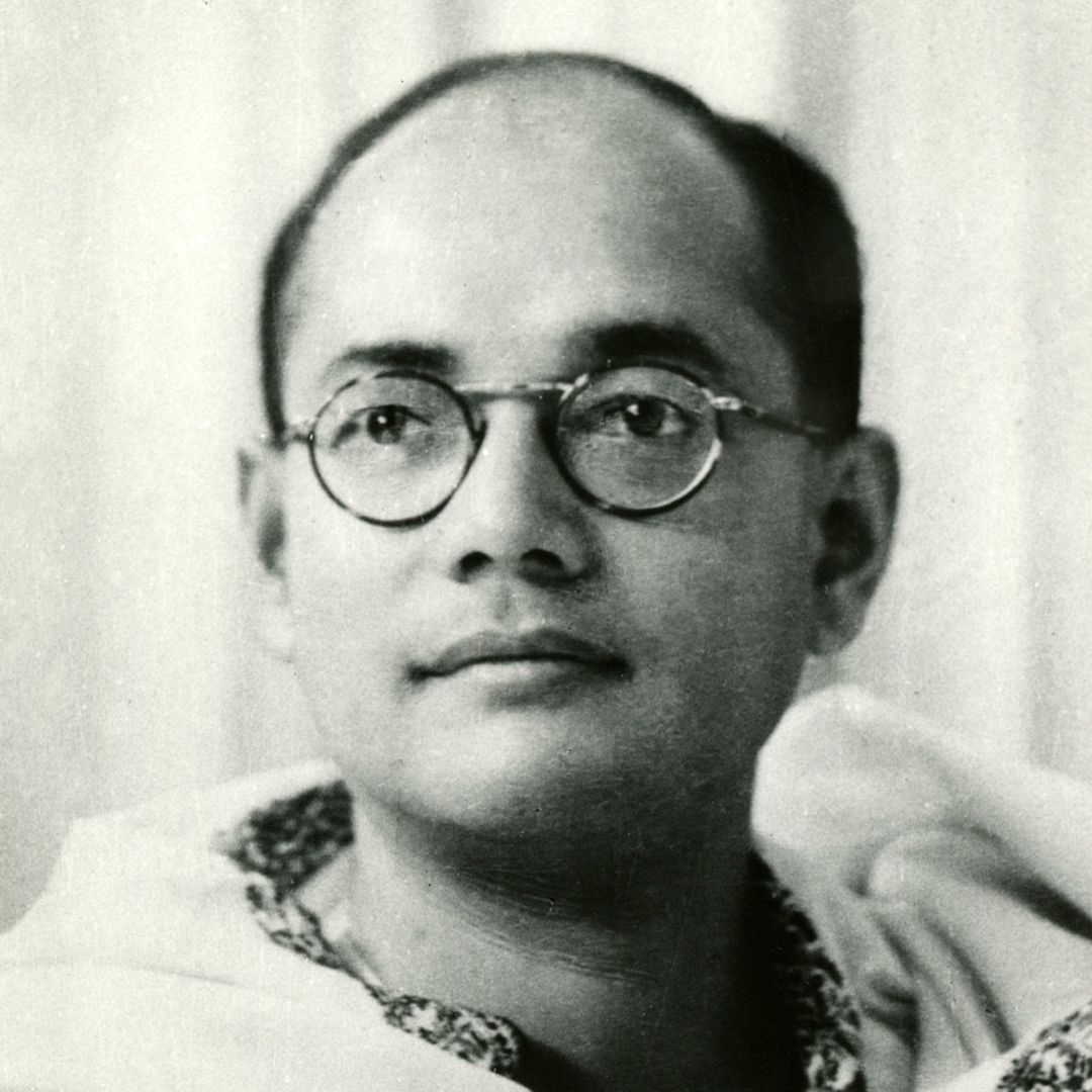 A black and white photo of a man in circular-rimmed spectacles and a white robe