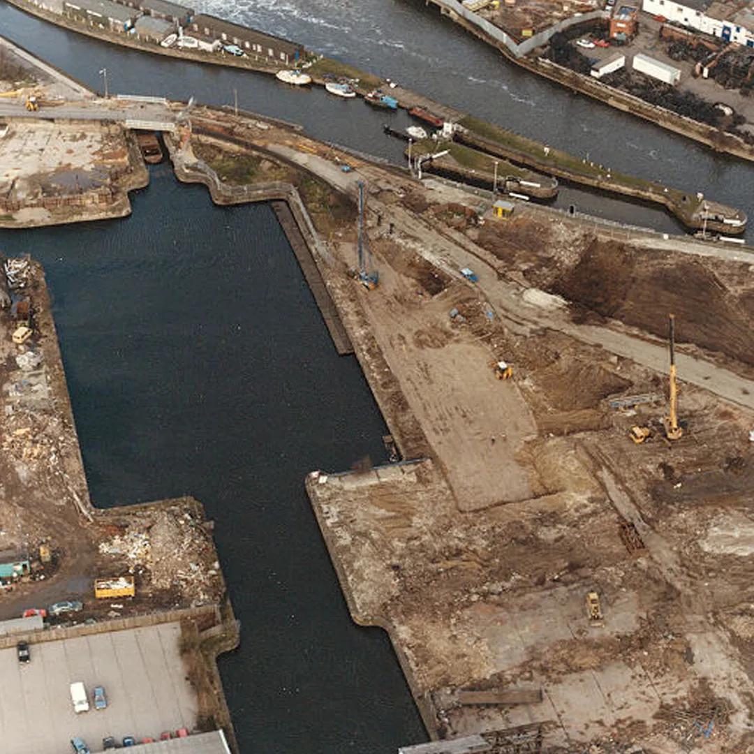 A colour photograph of a building site next to a dock, the future site for the Royal Armouries in Leeds