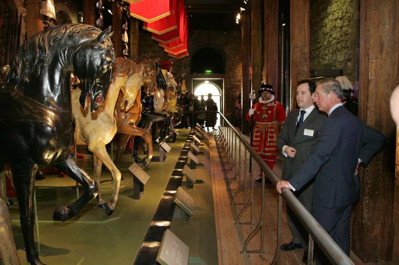 A colour photograph of two men look at a row of wooden horses