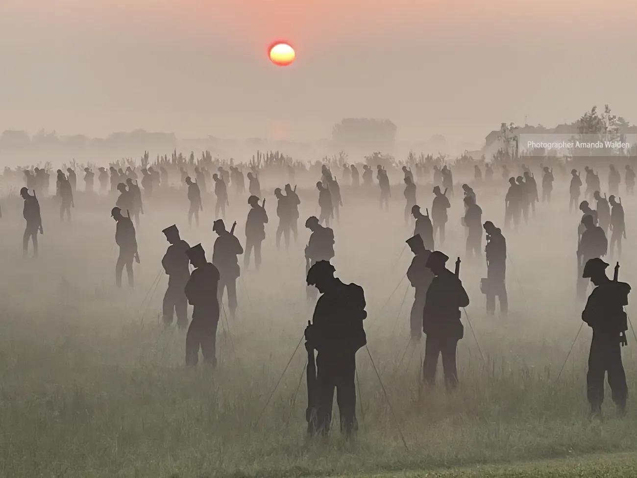 100s of life-sized silhouettes representing soldiers, in a field at dawn with mist on the ground - photographer Amanda Walden