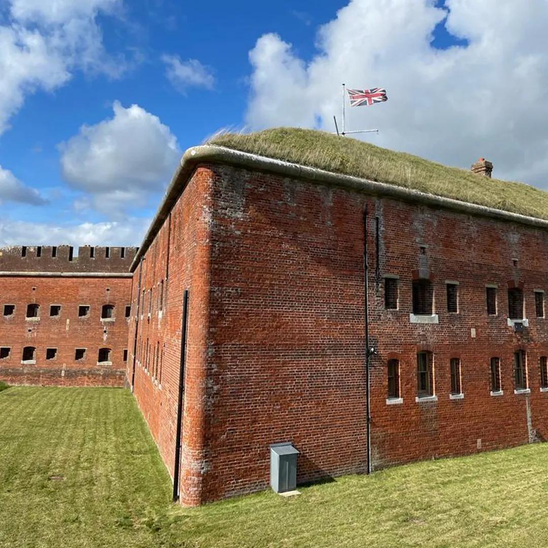 An external photo of a brick and earthwork fortification with windows cut into the wall