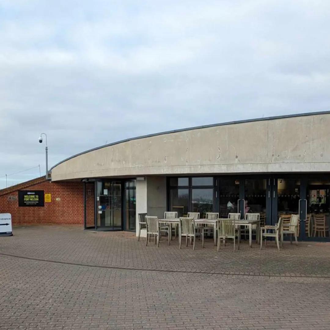 A exterior photo of a low building with a curved concrete roof and large glass windows