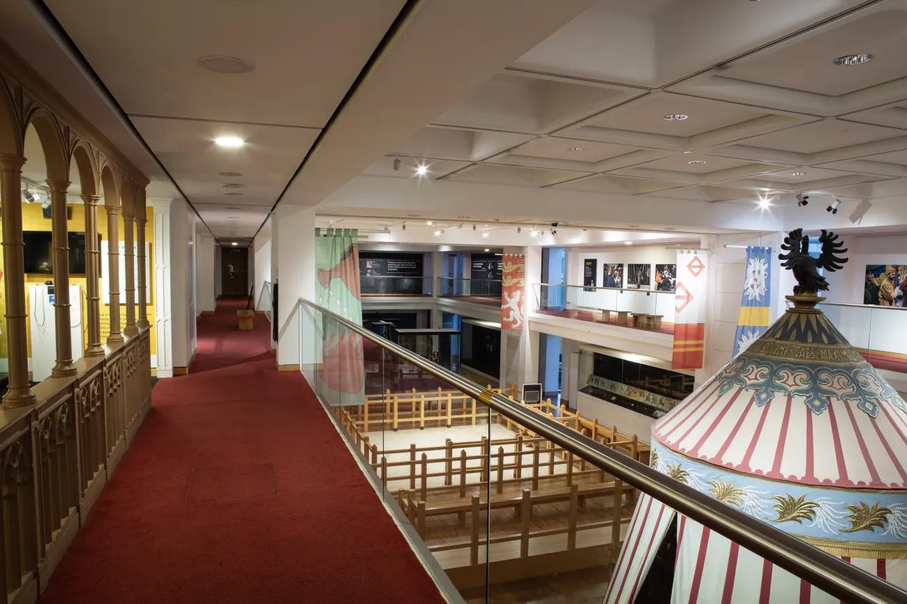 A broad view of the third floor tournament gallery, with red carpet and a balcony running around the edge.