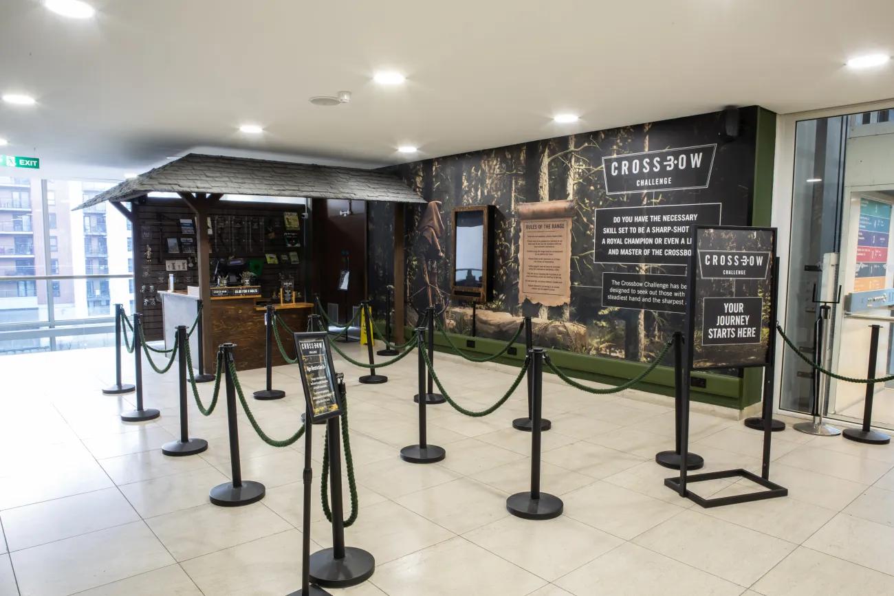 A roped waiting area outside a wooden kiosk with gifts and a till.