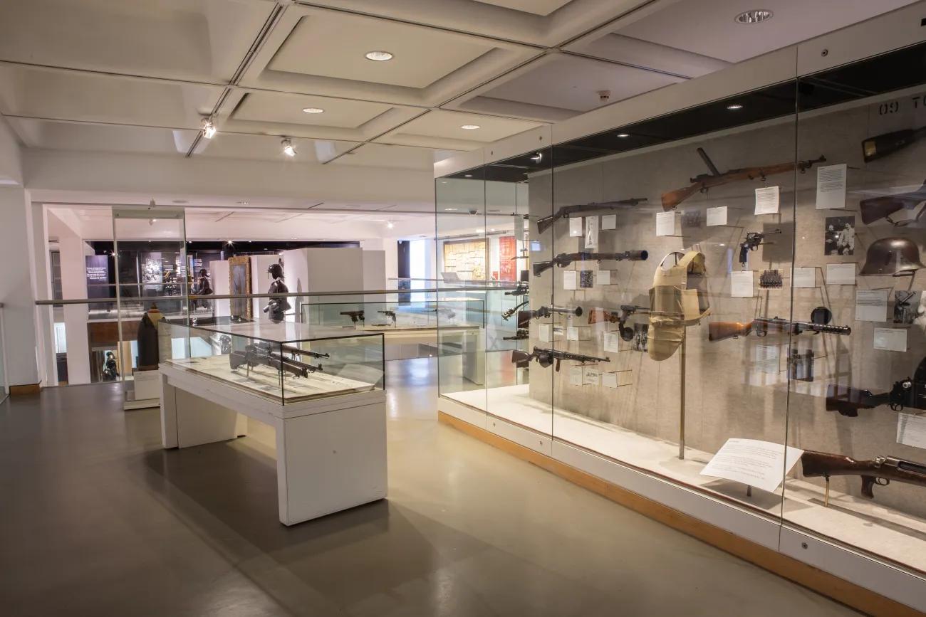 An overview of one section of a war gallery, including arms and armour from the First World War in glass cases.