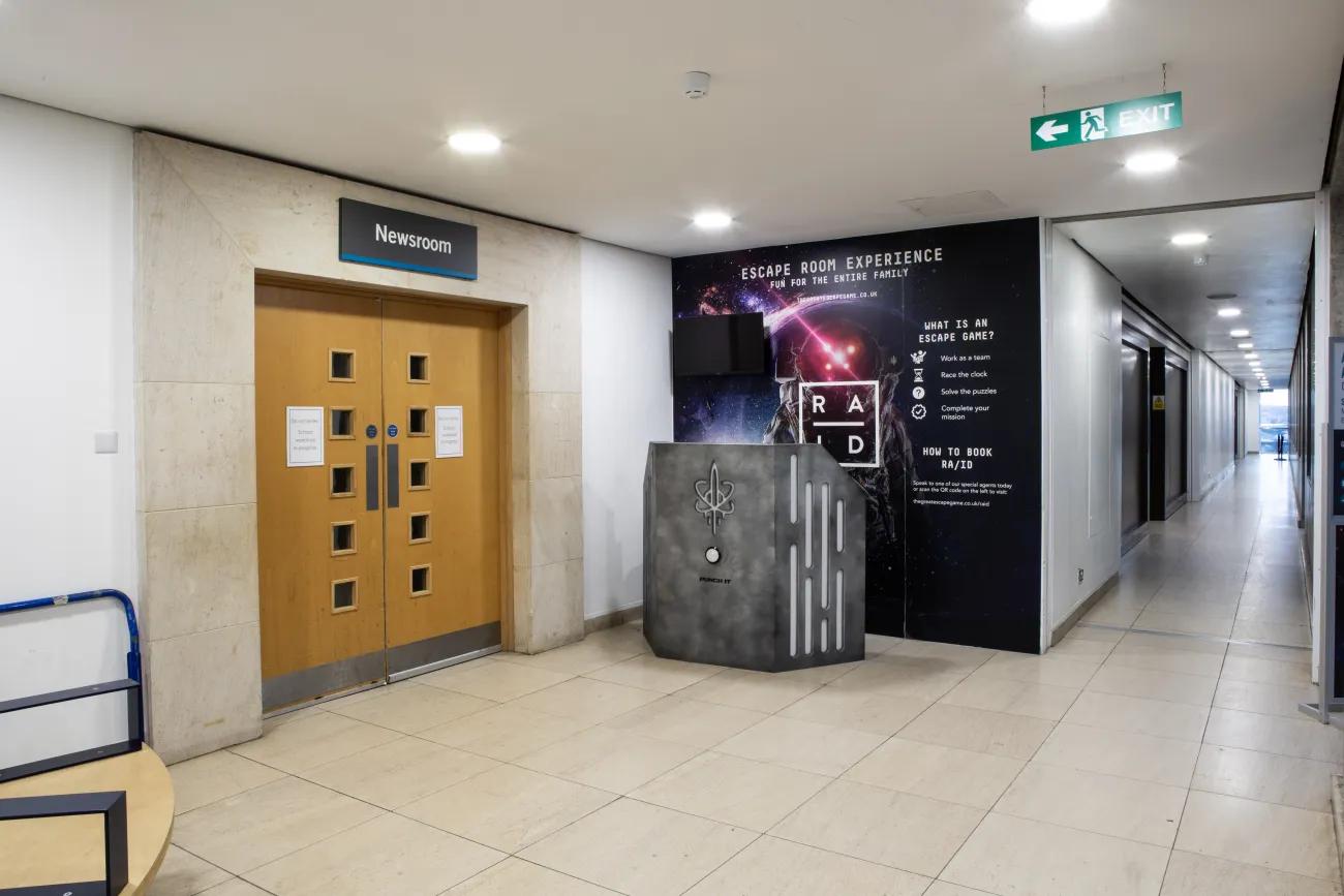 A photo of an open space with a dark, futuristic looking desk beside some double doors.