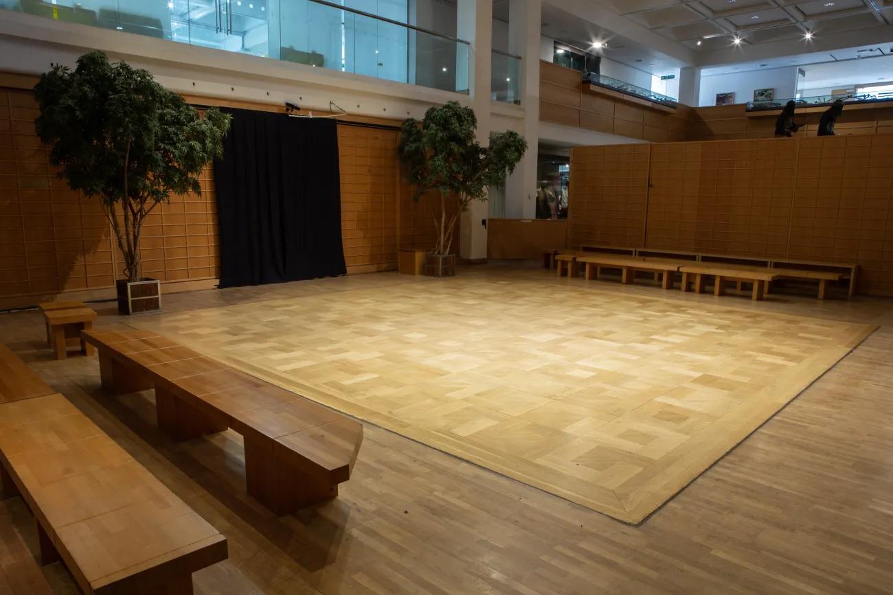 A wooden arena with Japanese inspired decor, flanked on either side with wooden benches