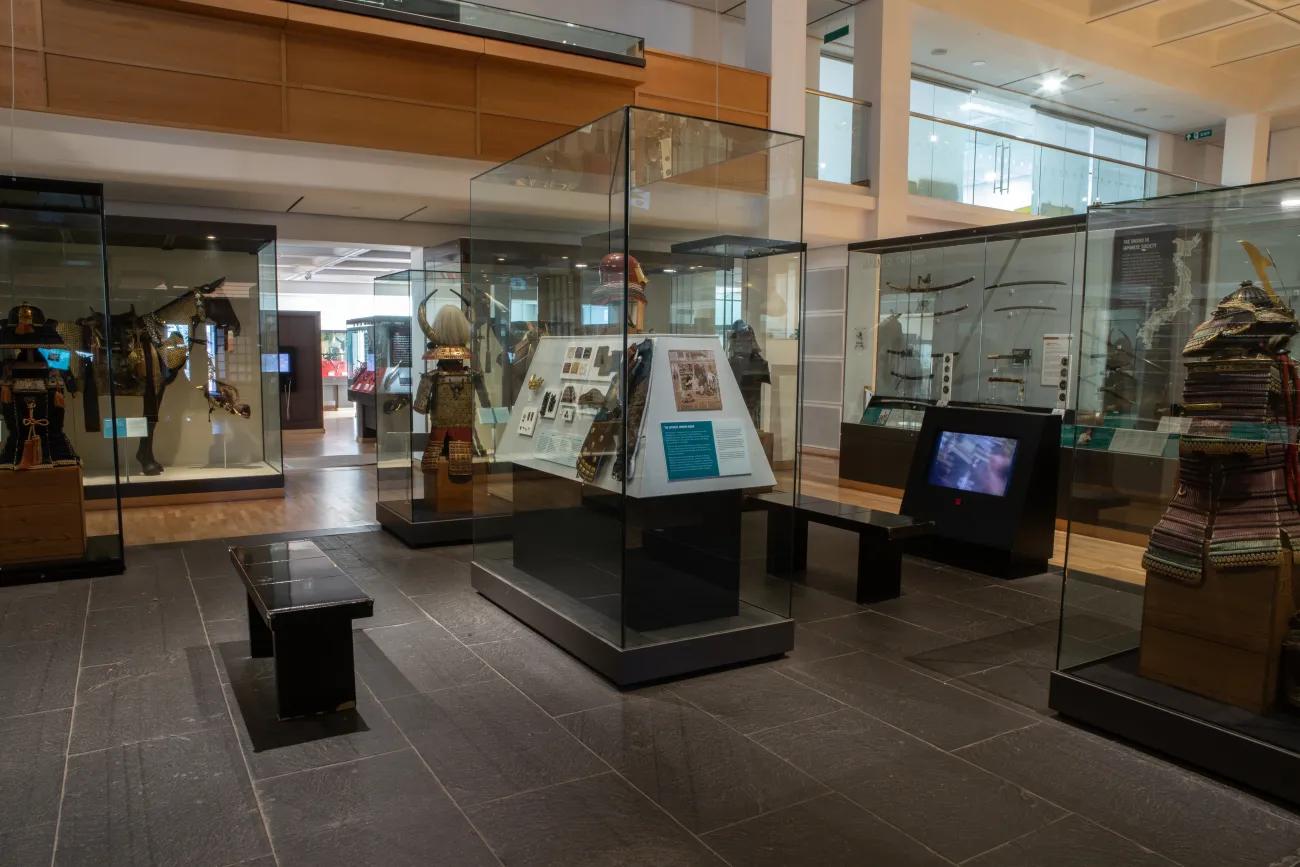 A room filled with glass cabinets containing examples of Japanese feudal weaponry