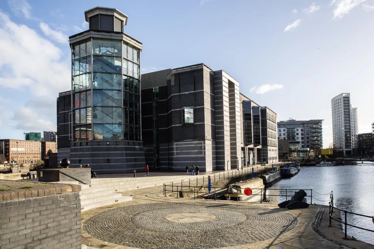 A large grey tower attached to a grey building sits besides a dock