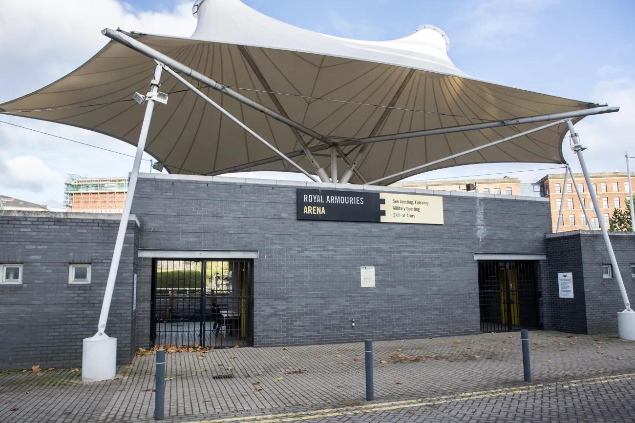 A grey wall with two black iron gates on either side, covered by a white canopy