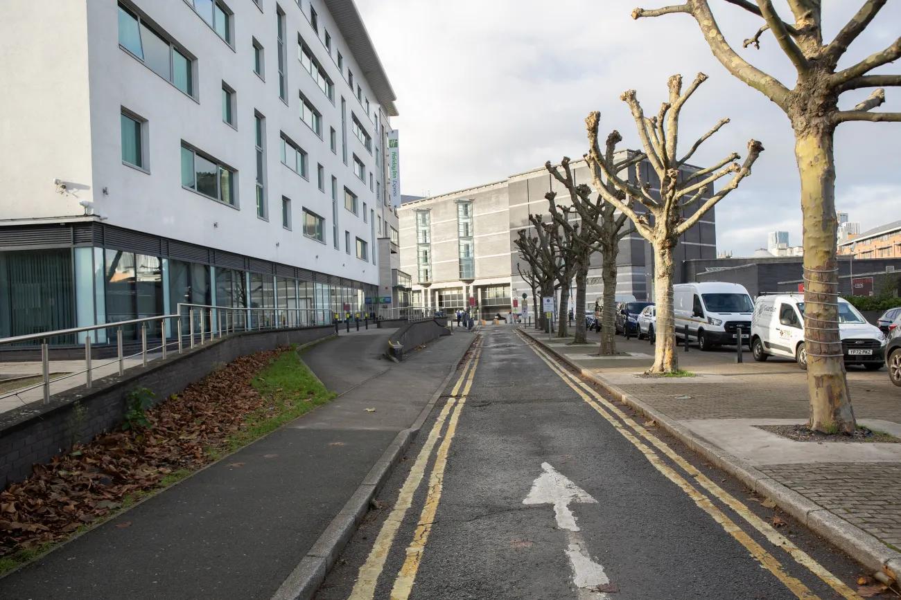 A colour photo showing a road leading to a large square flanked by bare trees