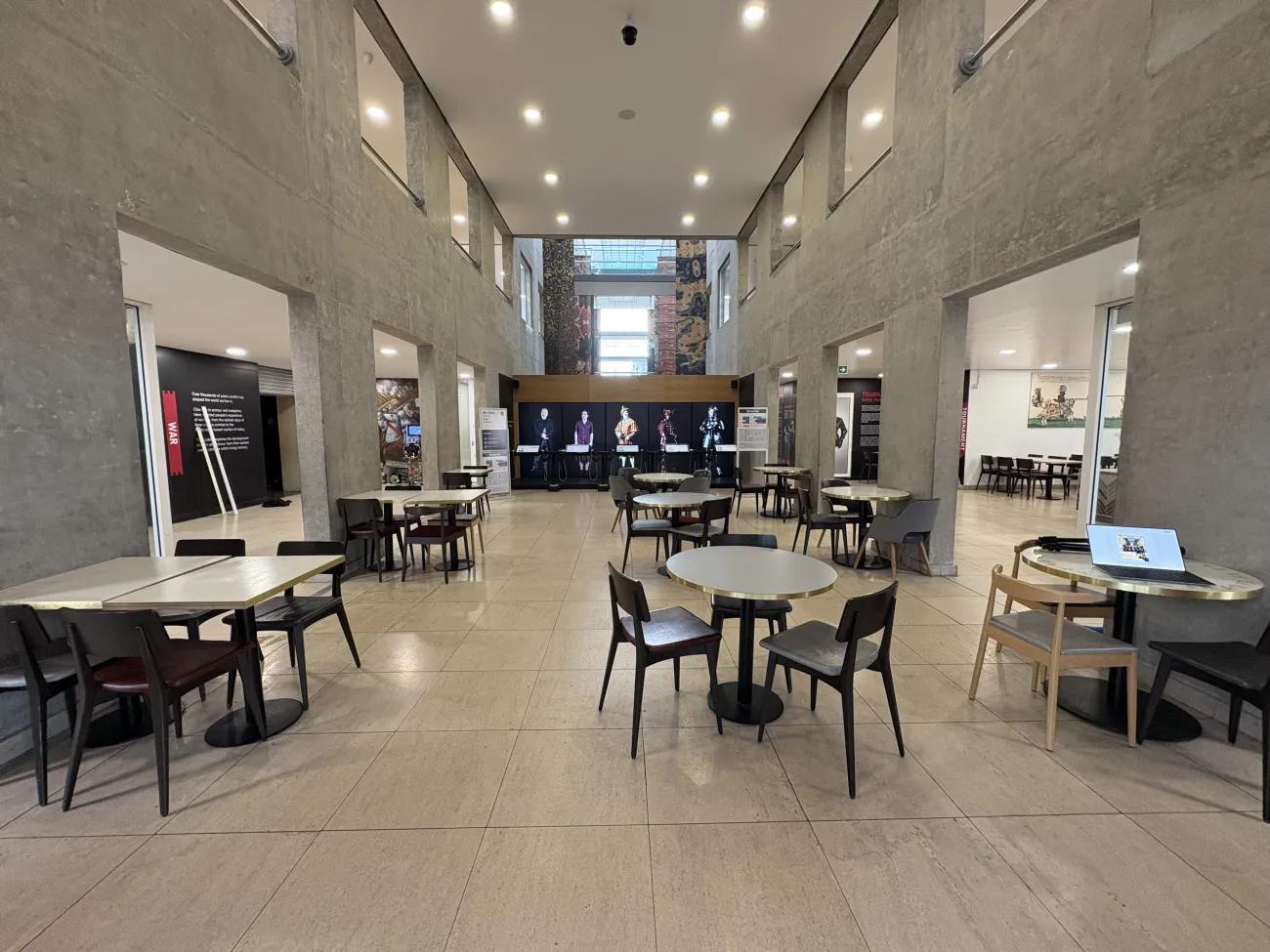 A wide open picnic space nestled between columns and with a five panelled digital display at the far end.