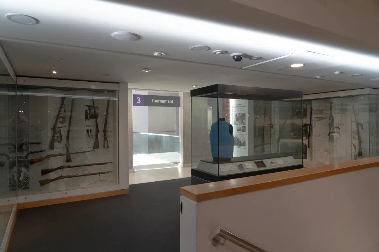 A blue flak style jacket in a glass case faces the entrance to a museum gallery