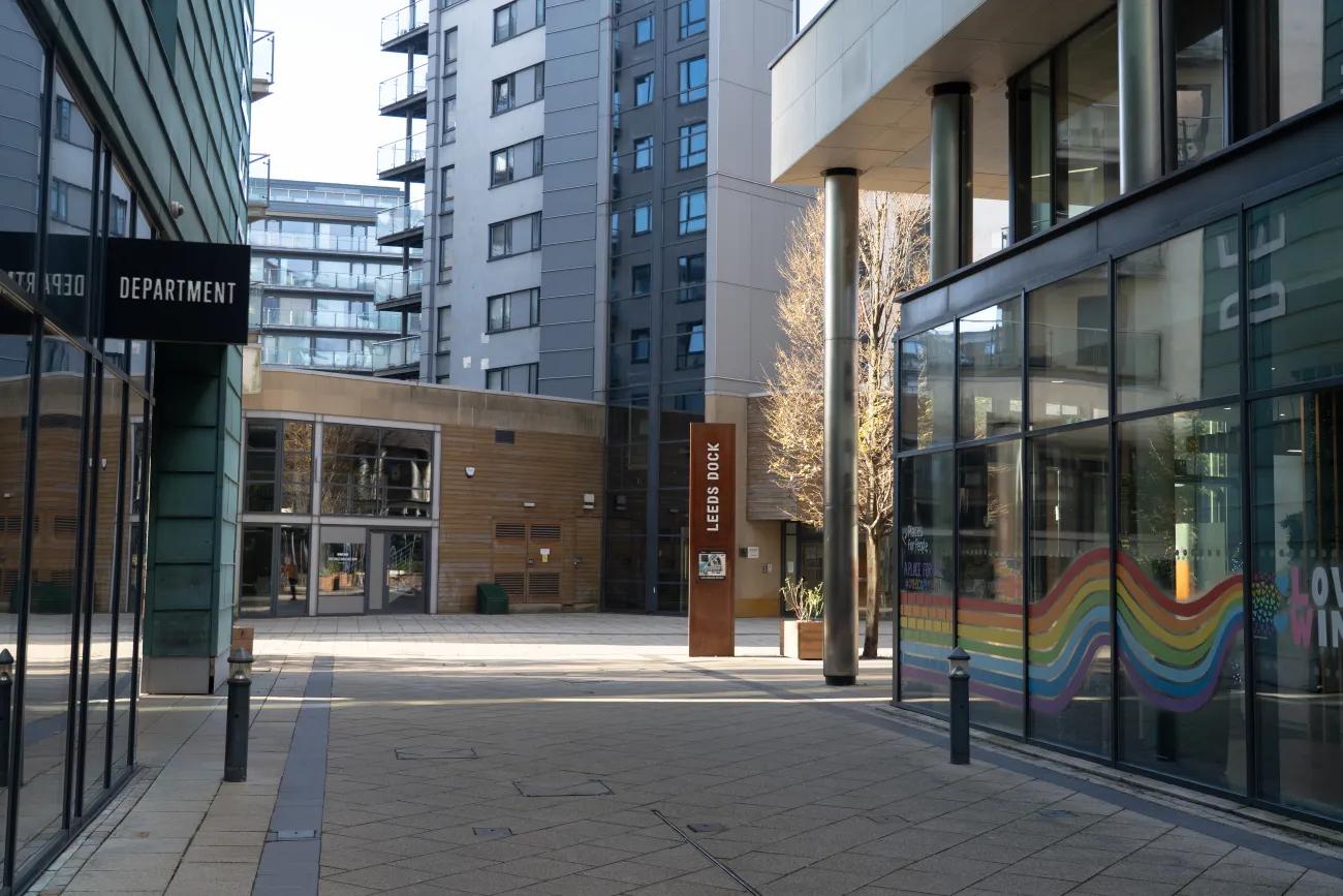 A photo of two buildings opposite one another over a wide alley. One is clad in copper green, the other has a long rainbow in the window.
