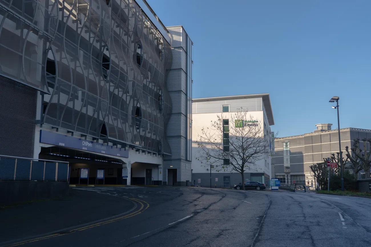 A photo of a large, steel-bound concrete carpark next door to a large white Holiday Inn