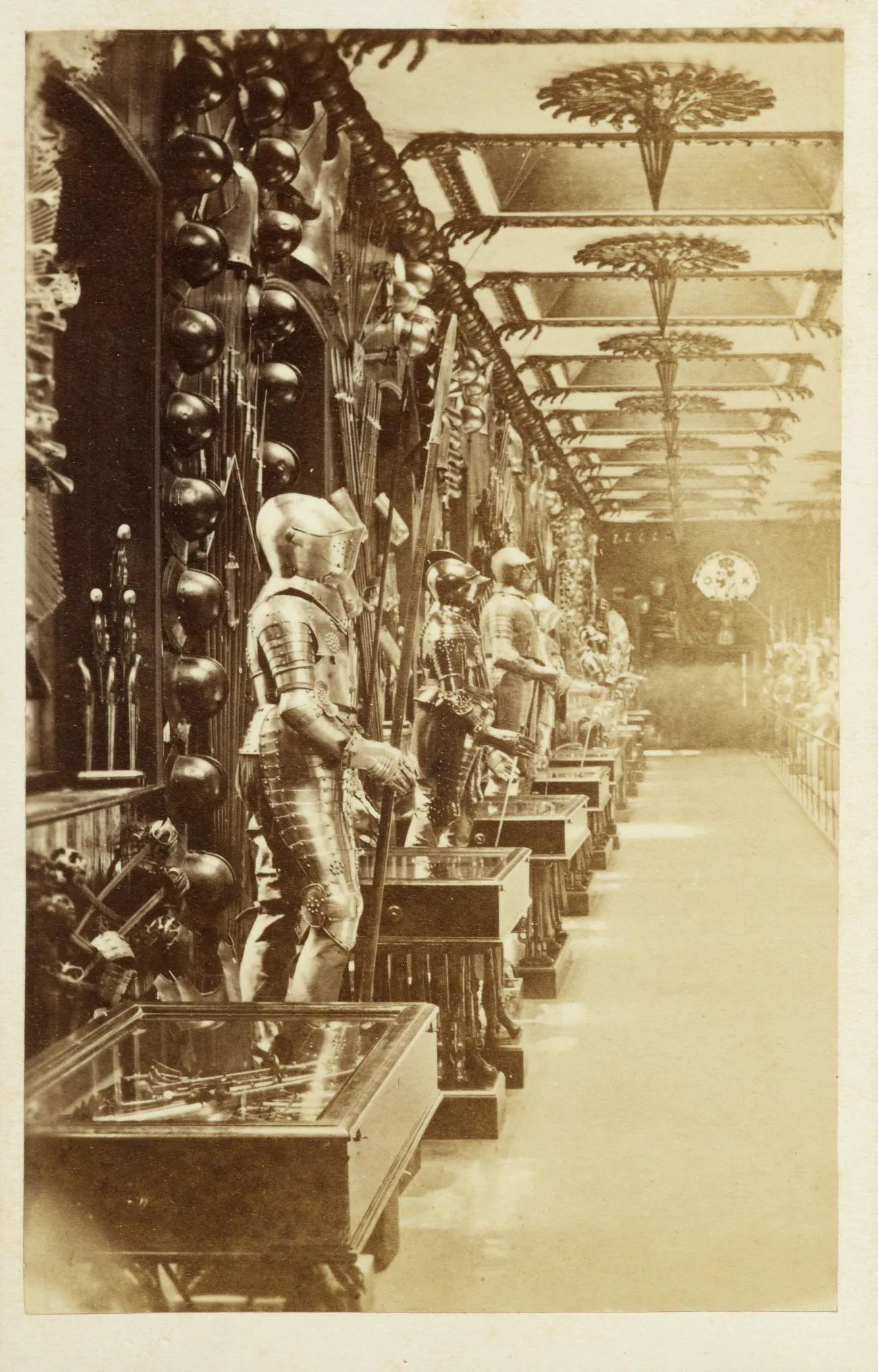 A sepia tone photograph in portrait showing a line of armoured mannequins with additional pieces lining the wall behind.