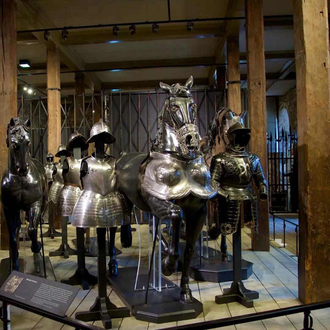 A colour photo of a display of armour located between wooden beams in a stone walled castle interior