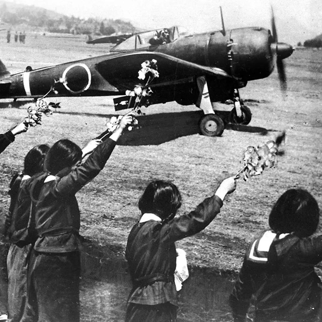 A black and white photo of Japanese schoolgirls waving off a kamikaze pilot in April 1945