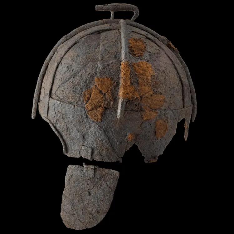 Helmet side on with orange rust in the middle and boar crest on top