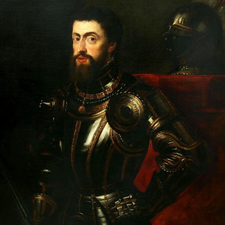 a bearded man poses wearing black and gold armour. His helmet sits behind his left shoulder on a red cloth.