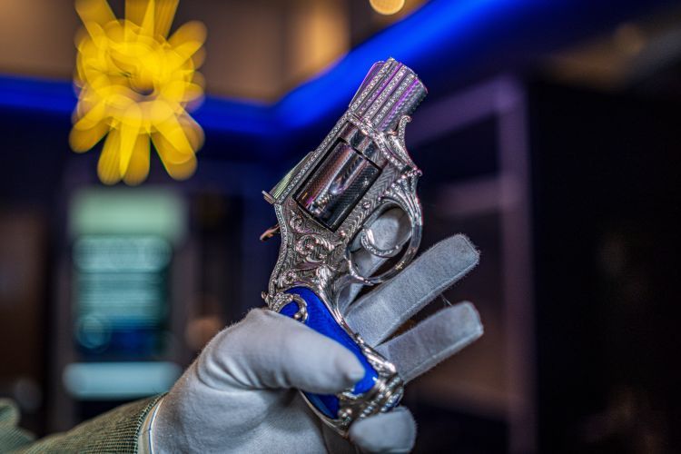 Gloved hand holding a diamond encrusted Smith and Wesson revolver 