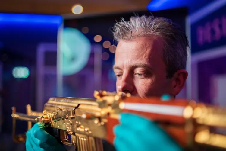 man carefully inspecting a golden A47 rifle
